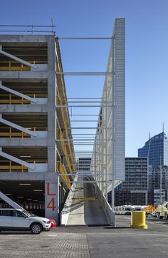 a car parked in front of a tall building with stairs on it's sides