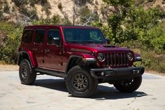 a red jeep is parked in front of some trees