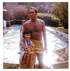 a man standing next to a young boy in front of a swimming pool