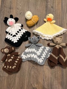 crocheted baby clothes and toys laid out on a wooden floor with yarn balls