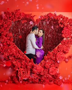 a man and woman standing next to each other in front of a heart shaped frame