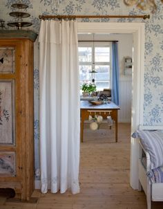 an open door leading to a bedroom with blue and white wallpaper