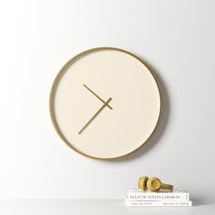 a white clock with gold trim on the face and two earphones sitting next to it