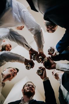 a group of people standing around each other holding cups in their hands and looking up at the sky