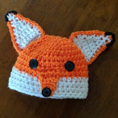 an orange and white crocheted hat with a fox design on it's face