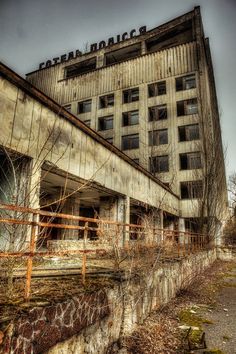 an old abandoned building with rusted metal railings and trees growing out of it