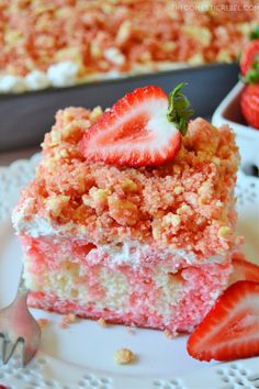 a piece of strawberry cake on a white plate with strawberries next to it and another slice in the background