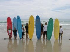 a group of people standing next to each other on top of a beach holding surfboards