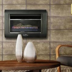 a wall mounted oven sitting on top of a wooden table next to two white vases