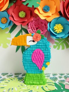 colorful paper flowers are arranged in the shape of a toucan with a bird on it