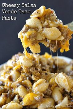 a spoon full of taco pasta being lifted from a bowl with the words cheesy salsa verde on it