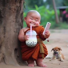 a baby with a cell phone next to a tree and a dog on the ground