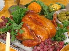 a turkey is sitting on a platter surrounded by grapes and vegetables