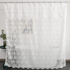 a white shower curtain hanging on the side of a bathroom wall next to a potted plant