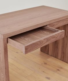 a close up of a wooden table on a hard wood floor with one drawer open