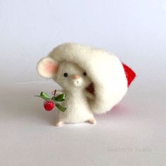 a small white mouse with a red hat on it's head holding a berry