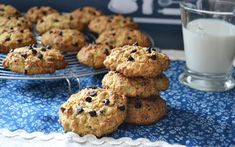 chocolate chip cookies and milk on a blue tablecloth next to a glass of milk