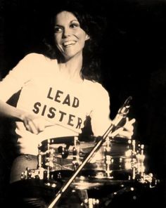 a woman is playing the drums while wearing a t - shirt that says lead sister