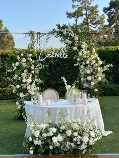 a table set up with white flowers and candles for an outdoor wedding reception in the garden