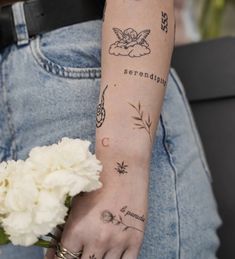 a woman's arm with tattoos on it and flowers in the middle of her arm