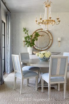 a dining room table with four chairs and a chandelier in the back ground