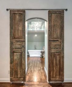 an open door leading to a bathroom with a chandelier hanging from the ceiling