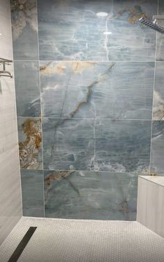 a bathroom with marble walls and flooring in the shower area is pictured here, it appears to be tiled