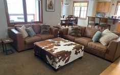 a living room filled with furniture and a cow print ottoman