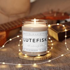 a lit candle sitting on top of a wooden table next to a string of lights