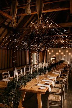 a long table with white plates and place settings is set up in the middle of an old barn