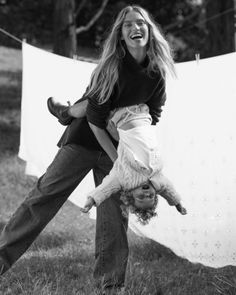 two women are playing with each other in the grass while hanging laundry on a line