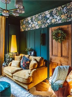 a living room with green walls and floral wallpaper on the walls, two couches in front of an open door