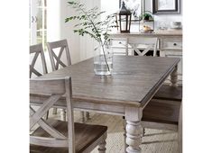 a dining room table with chairs and a vase filled with flowers on top of it