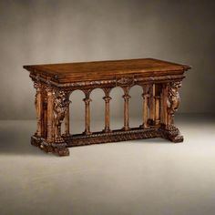 an old wooden table with carvings on the top and bottom, sitting in front of a gray background