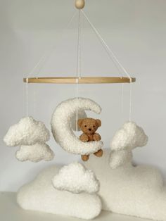 a teddy bear sitting on top of a cloud like structure that is suspended from the ceiling