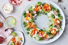 a white plate topped with a salad covered in toppings next to other food items