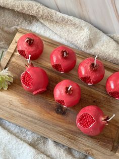 four red apples are sitting on a cutting board