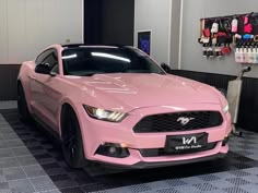 a pink mustang car is parked in a showroom