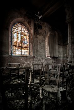 an old church with stained glass windows and wooden chairs in the foreground, dark background