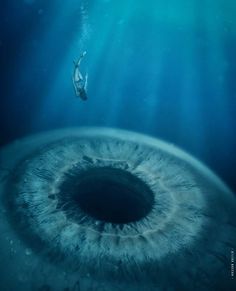 a man swimming in the ocean with an eyeball shaped object above him and below water