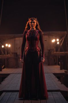 a woman dressed as captain america stands on a dock at night with lights in the background