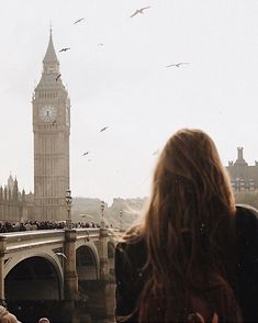 a woman is looking at the big ben clock tower