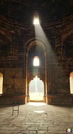 the sun shines through an arched window into a stone building