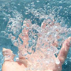 someone is swimming in the blue water with their hand out to touch it's surface