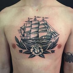 a man's chest with a ship and rose tattoo on it