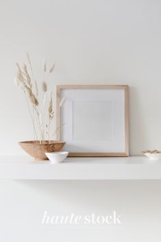 a white shelf topped with two bowls filled with flowers and a framed photo next to it