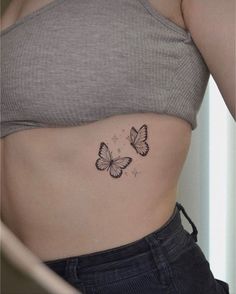 a woman's stomach with two butterflies tattoo on the side of her belly,