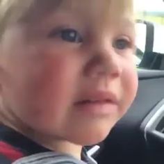 a little boy sitting in the back seat of a car looking at something off to the side