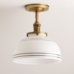 a white and gold ceiling light hanging from a ceiling fixture in a room with gray walls