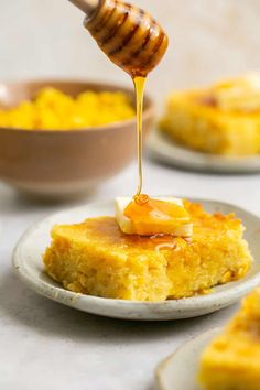 honey being drizzled onto a piece of cake on top of a plate